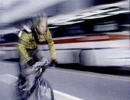 A cyclist riding fast along a city road.