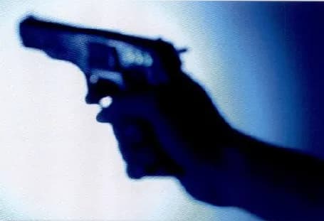 A hand holding a gun, seen in dark blue light.