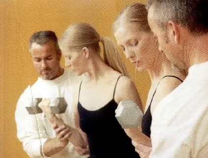 A small group exercising with dumbbells while an instructor shows them what to do.