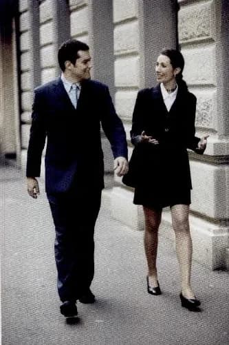 A man and a woman in smart business clothes walking along a city street.