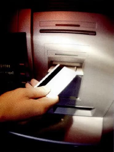 A hand putting a bank card into a cash machine.